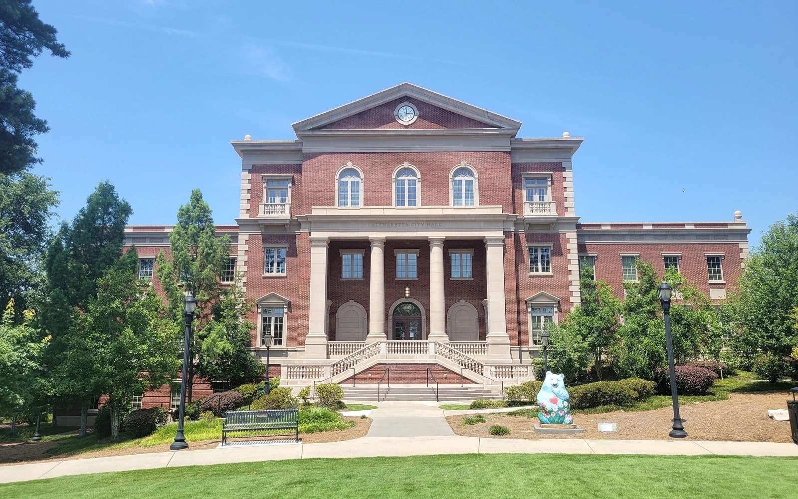 Red-brick Alpharetta City Hall, with a columned entrance, a clock and a broad lawn in front.