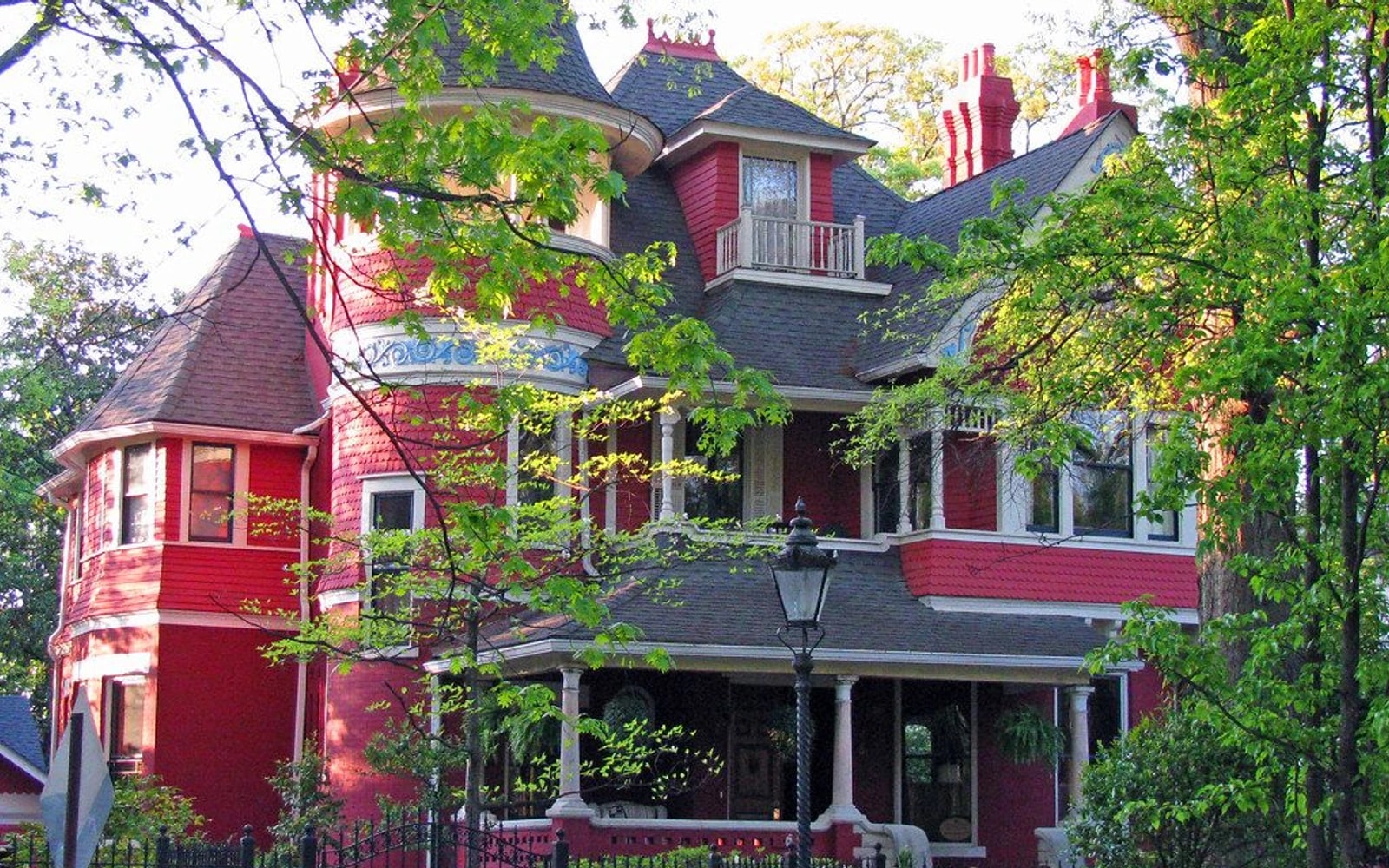 Large red-and-white house partly shaded by leafy trees in Atlanta’s Inman Park neighborhood.