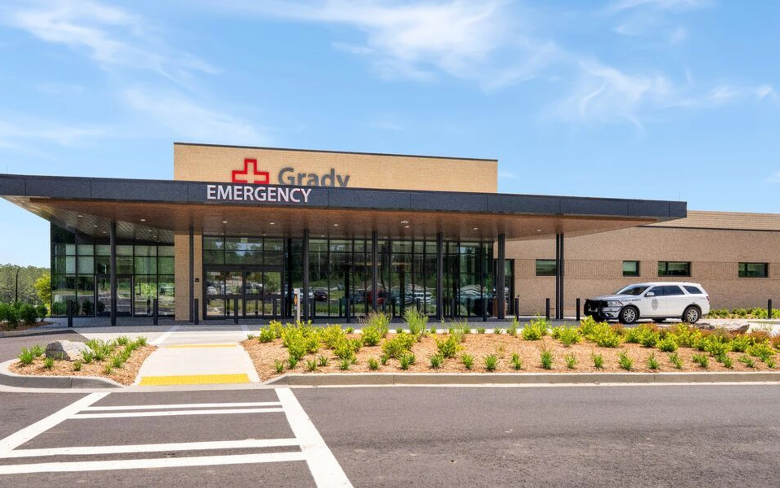 Grady South’s single-story emergency department, with Grady and Emergency signs above a glass entrance and a crosswalk leading toward the doors.