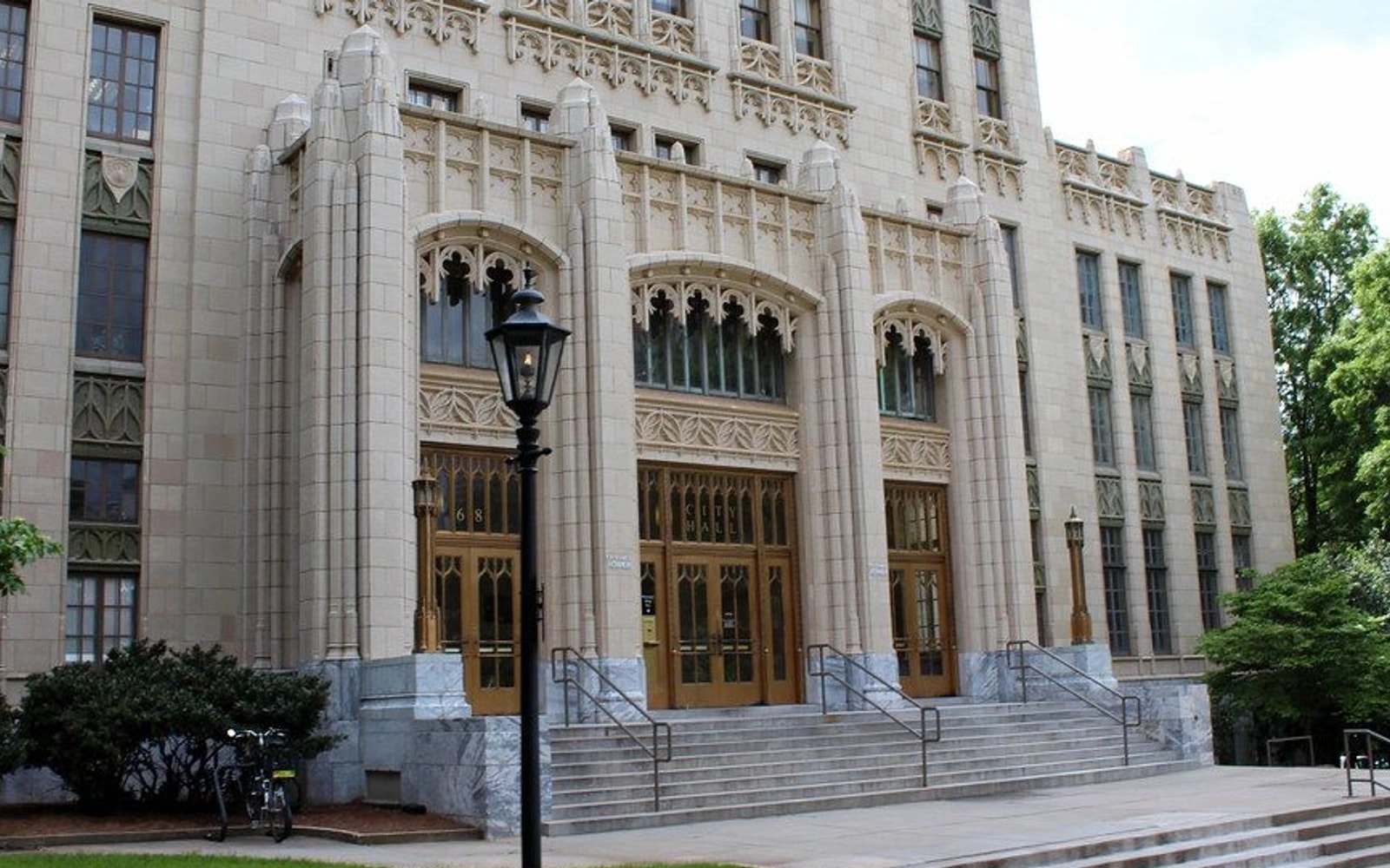 The ornate stone entrance and broad steps of Atlanta City Hall, partly framed by trees, in daylight.