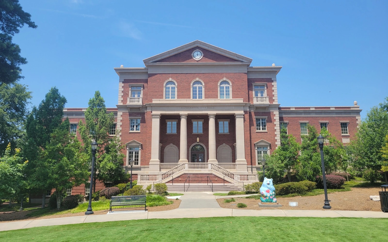 Alpharetta City Hall, a red-brick civic building with a central portico, landscaped grounds and lawn.