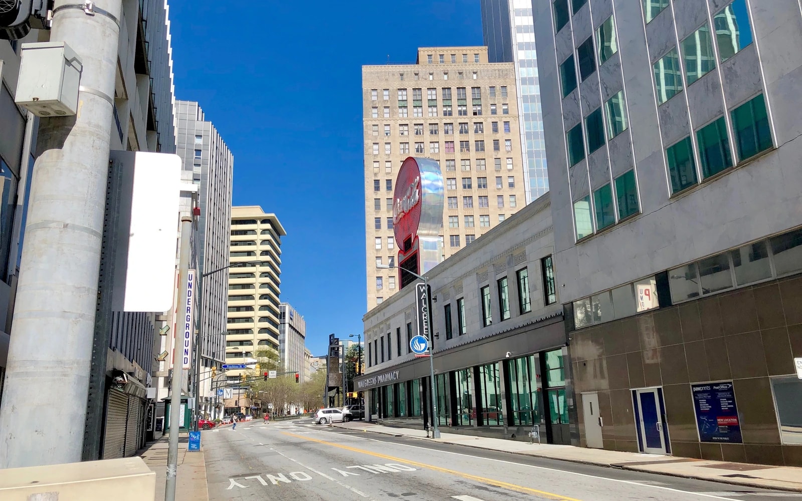View along an Atlanta street lined with multistory buildings, with storefront windows and directional markings on the roadway.